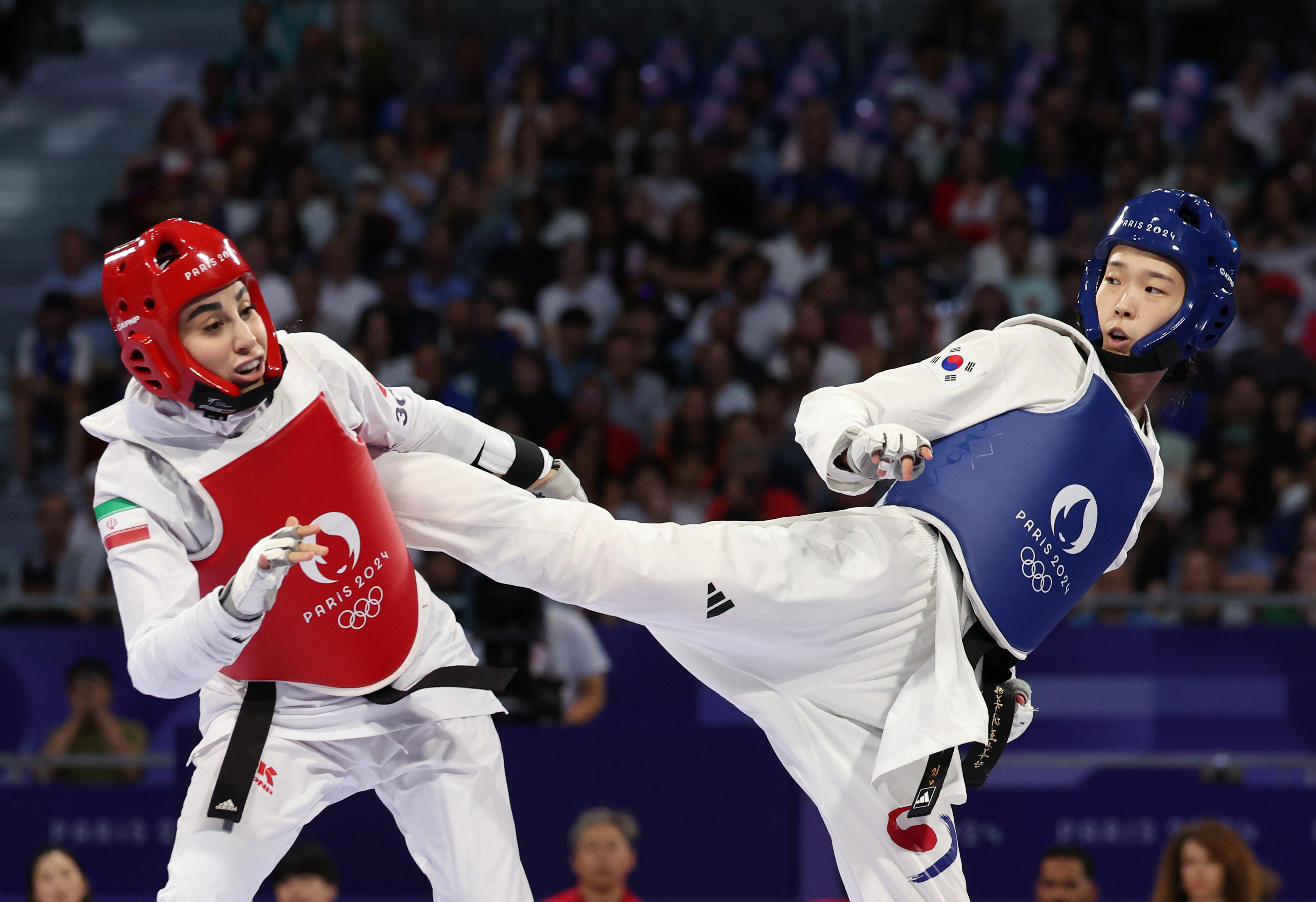 Kim Yujin (right) on Aug. 8 kicks opponent Nahid Kiyanichandeh of Iran in the 57-kg final of women's taekwondo at the Grand Palais in Paris.  