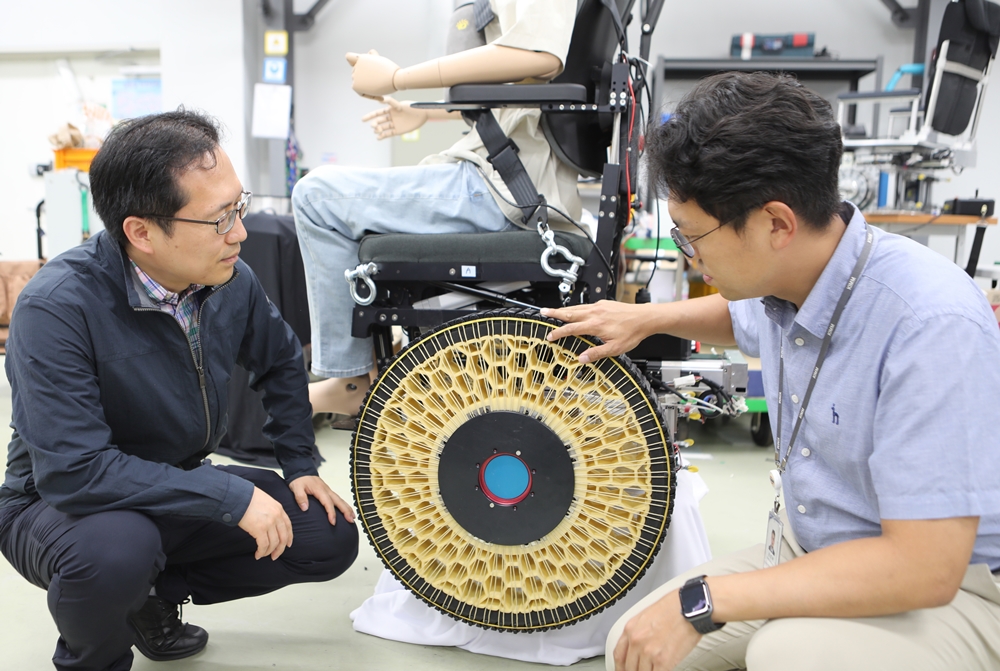 Song Sung-Hyuk (right), a senior researcher at the Advanced Robotics Center of the Korea Institute of Machinery and Materials, and center director Kim Dong Il inspect a wheelchair with the morphing wheels they invented. 
