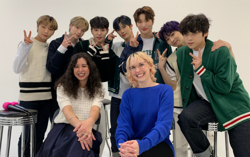 Co-hosts Angélica Davila and Shannon Locke pose for a photograph with K-pop boy group BLITZERS, who appeared as guests on the podcast.