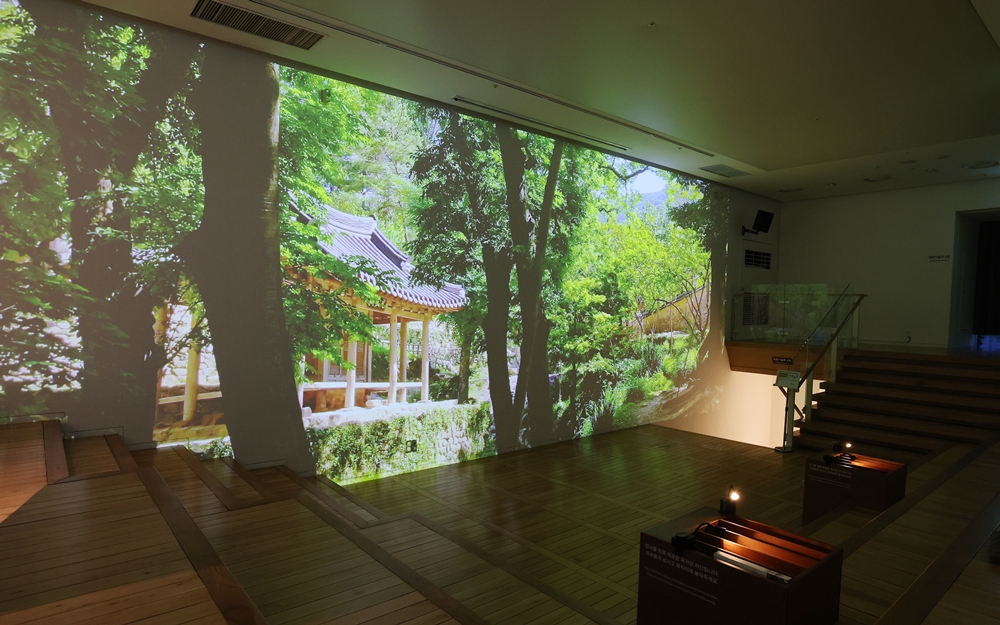 A video using the chagyeong (borrowed scenery) technique, a concept in traditional Korean architecture of enjoying the outside view from a window like it was a painting in a frame, features traditional landscaping at the entrance of the exhibition 