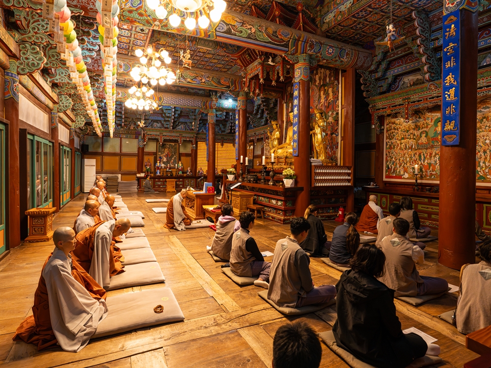 Foreign reporters and monks at Baekysangsa Temple on May 3 hold a morning prayer service at Daewoongjeon Hall, the main hall of the temple decorated with dancheong, or traditional architectural designs on the wooden buildings of temples, palaces and shrines.