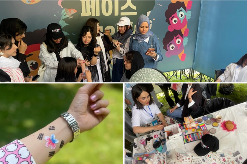 Visitors experience face and body painting featuring Korean symbols at the Face Painting Booth.
