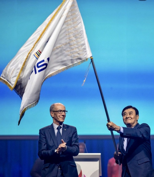Korea's Chungcheong region on July 27 officially received the official flag of the 2027 Summer Universiade from FISU, the global governing body for collegiate sports, at the closing ceremony of this year's Rhine-Ruhr Summer World University Games in Duisburg, Germany. Shown is Kang Chang-hee, chairman of the Chungcheong competition's organizing committee, waving the flag next to FISU President Leonz Eder. (FISU's official Instagram account) 