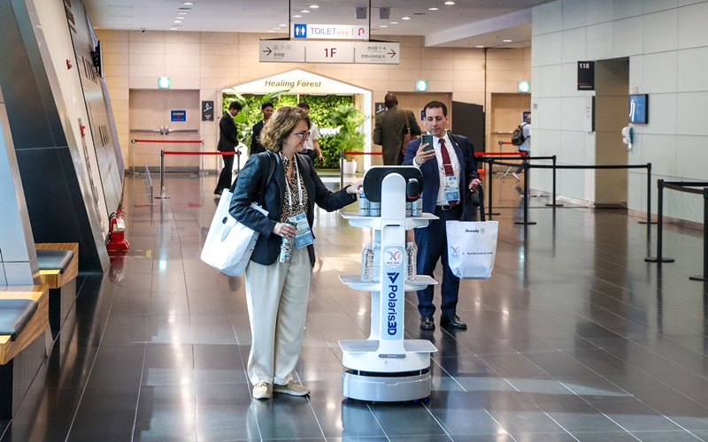 A participant on Aug. 5 receives bottled water from a robot at the third APEC Senior Officials' Meeting and Related Meetings at the convention facility Songdo Convensia in Incheon's Yeonsu-gu District. (APEC 2025's official Flickr account) 
