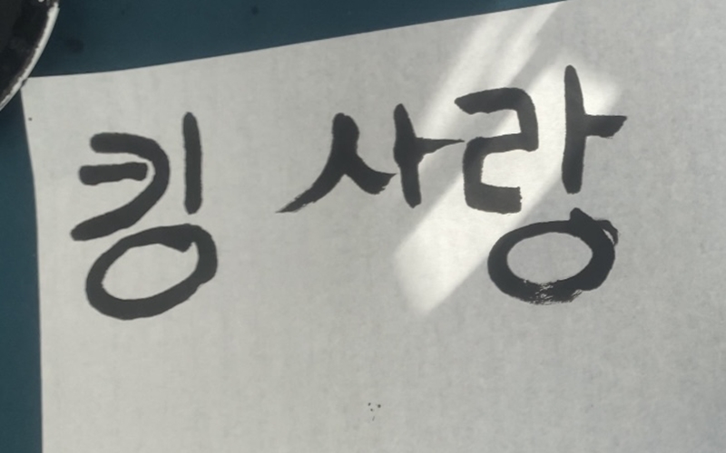 Trying calligraphy at the 2025 K-Festival.