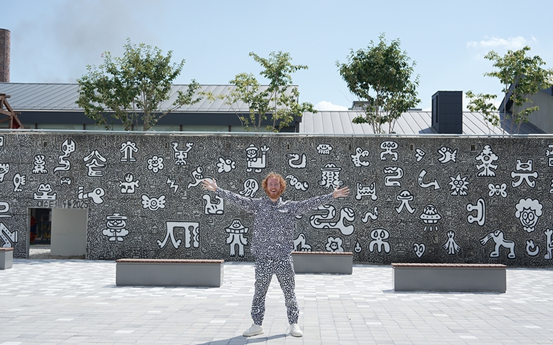 British doodle artist Sam Cox, widely known as Mr Doodle, poses in front of his massive 20-meter-wide, 4-meter-tall mural, created live on September 2 at the outer wall of the Jochiwon 1927 Art Center. [Image Courtesy: Sam Cox]