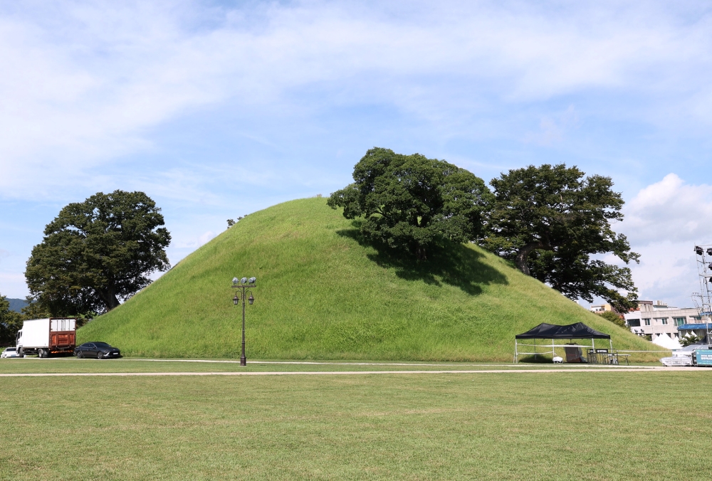 The imposing size of Bonghwangdae Tomb makes the surrounding vehicles look like toys. 