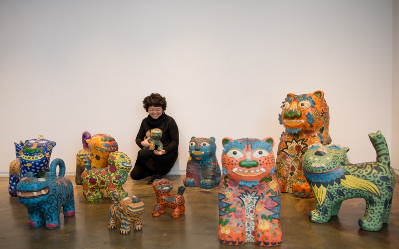 Artist Jang Mee-kyung, widely known for her vibrant ceramic tiger sculptures, poses with her works. (Courtesy of Jang Mee-kyung)