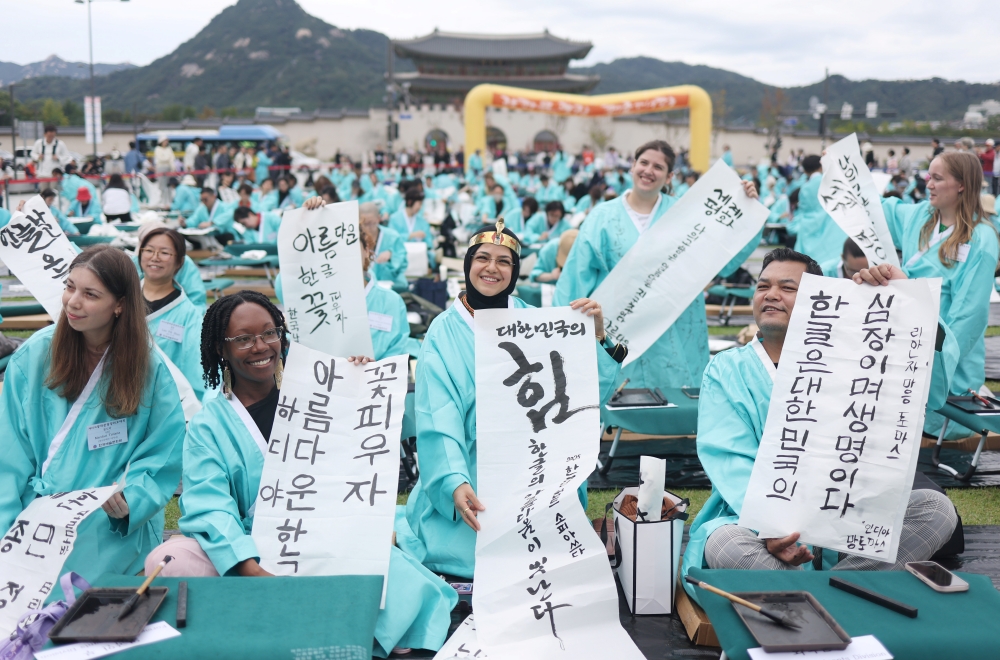 The number of people taking the Test of Proficiency in Korean, aka TOPIK, has surpassed 550,000 this year. Shown are foreign contestants on Oct. 9 displaying their entries in a Hangeul calligraphy competition to mark the 579th anniversary of Hangeul Day at Gwanghwamun Square in Seoul's Jongno-gu District. (Yonhap News) 