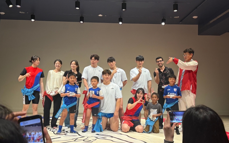 Ssireum athetles from the Korean Ssireum Association posing with volunteers of all ages who joined the friendly wrestling matches.