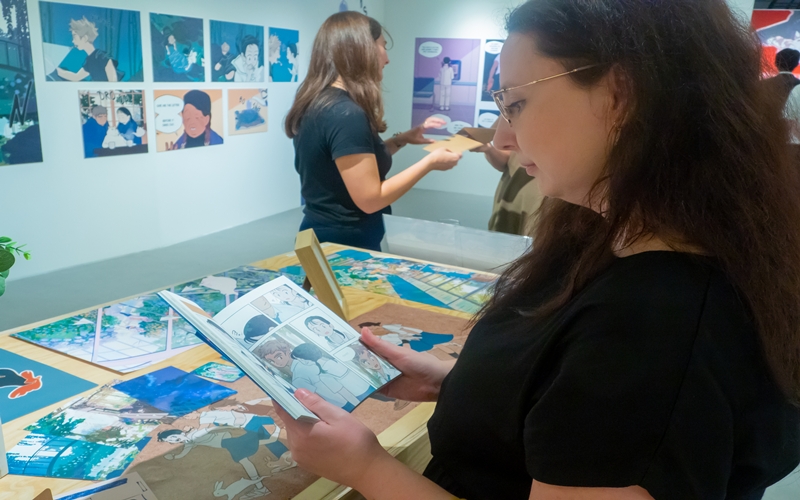 Honorary reporter Magdolna Magonyi reading a printed webtoon during the first guided tour of the K-Comics World exhibition. 