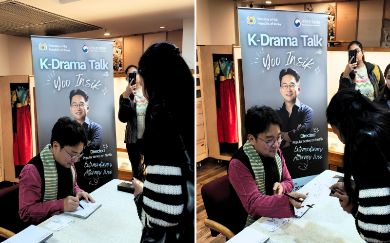 Yoo signs an autograph for a fan in a polite exchange.