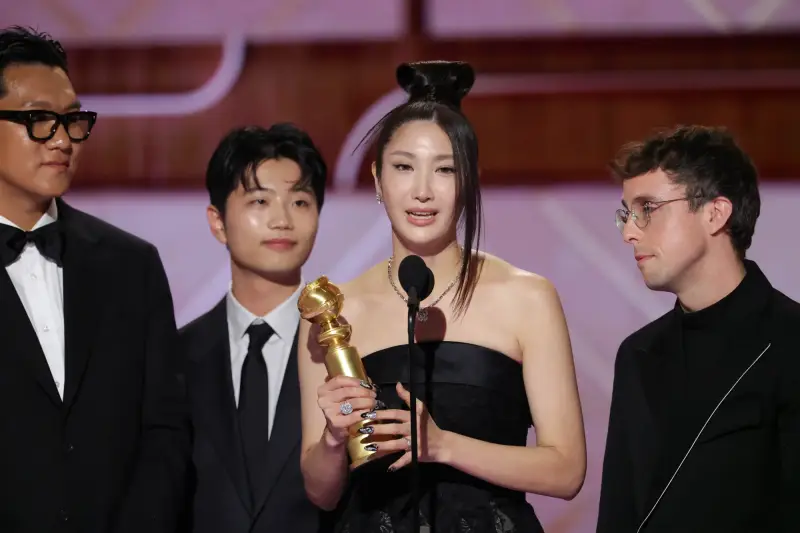 Singer-songwriter EJAE (second from right) on Jan. 11 gives a speech after receiving the Golden Globe for best original song from a film at the awards ceremony held at the hotel Beverly Hilton in Los Angeles.