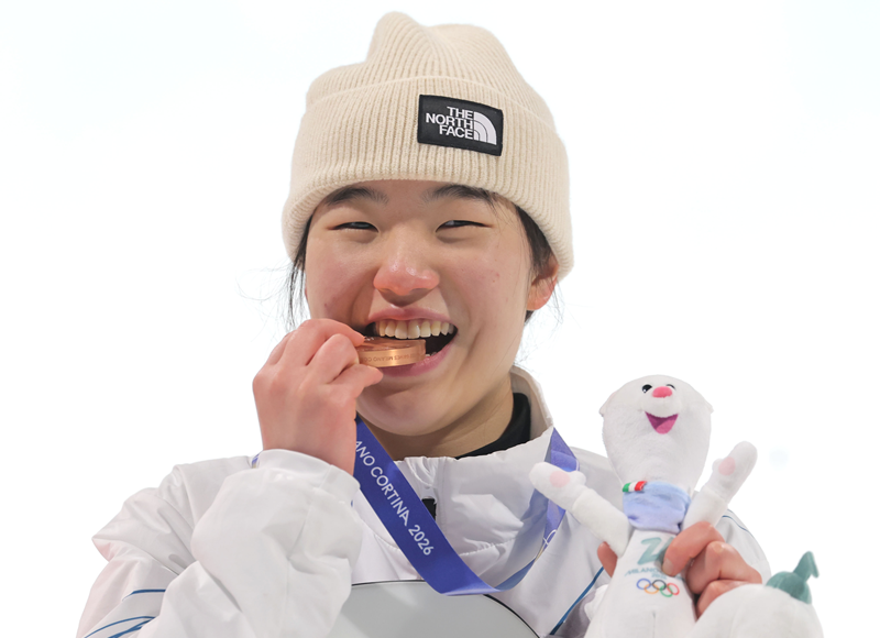 National snowboarder Yu Seungeun on Feb. 9 bites into her bronze medal won in women's big air at the Milan Cortina Winter Olympics at Livigno Snow Park in Livigno, Italy. (Yonhap News) 