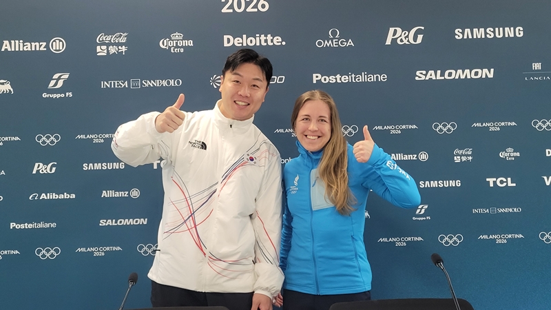 Former national bobsledder Won Yunjong (left) and Estonian biathlete Johanna Taliharm on Feb. 19 give a thumbs up at the athletes' village for the Milan Cortina Winter Olympics in Italy after being elected to the International Olympic Committee Athletes' Commission.