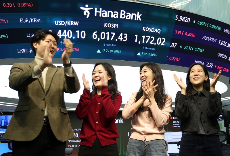 Dealers on Feb. 25 celebrate the main stock market KOSPI's historic crossing of 6,000 in front of the electronic billboard at the dealing room of Hana Bank headquarters in Seoul's Jung-gu District. (Yonhap News)  