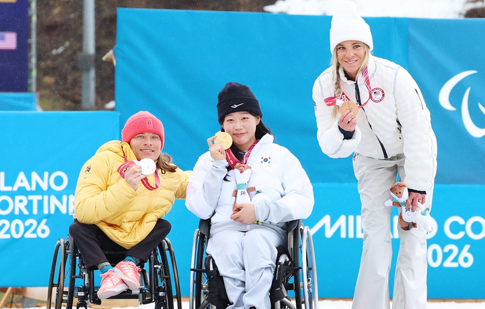 Kim Yunji (center) on March 15 holds her gold medal at the winners' ceremony for the 20-km interval start sitting race of women's cross-country skiing at the Tesero Cross-Country Skiing Stadium in the village of Tesero, Italy. 