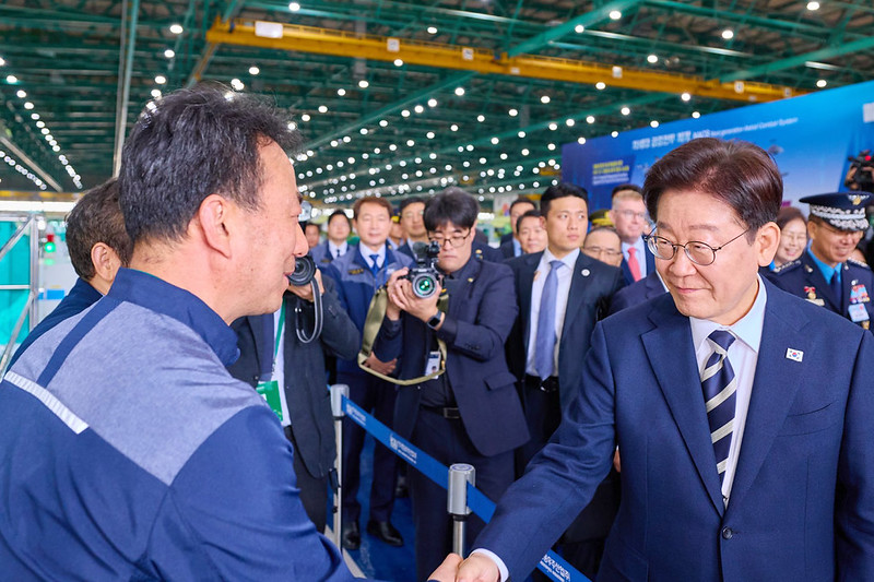 President Lee Jae Myung (right) on March 25 meets staff at the building for fixed-wing aircraft production at the Korea Aerospace Industries compound in Sacheon, Gyeongsangnam-do Province. 