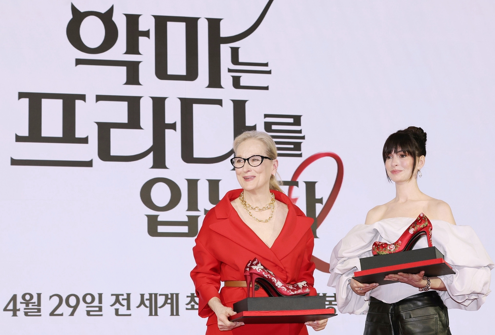 Actors Meryl Streep (left) and Anne Hathaway on April 8 pose with their customized high heels that reinterpret traditional Korean flower shoes at a news conference for the film 