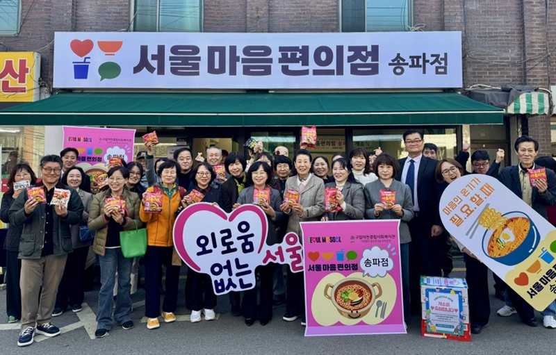 Officials and residents on April 7 pose for a group photo at the opening ceremony for the branch of Seoul Mind Convenience Store in Seoul's Songpa-gu District. Attendees hold packets of ramyeon (instant noddles), the chain's symbol, and placards reading 