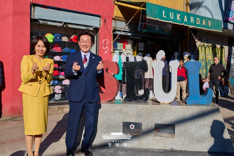 President Lee and first lady Kim on July 30 make the heart finger gesture to ethnic Koreans and residents in front of the Seoul Street monument in the Patronato neighborhood of Santiago's Recoleta District. 