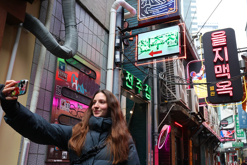 A woman on Dec. 10, 2025, takes a selfie at an alley of the Euljiro area in Seoul's Jung-gu District. (Korea.net DB)