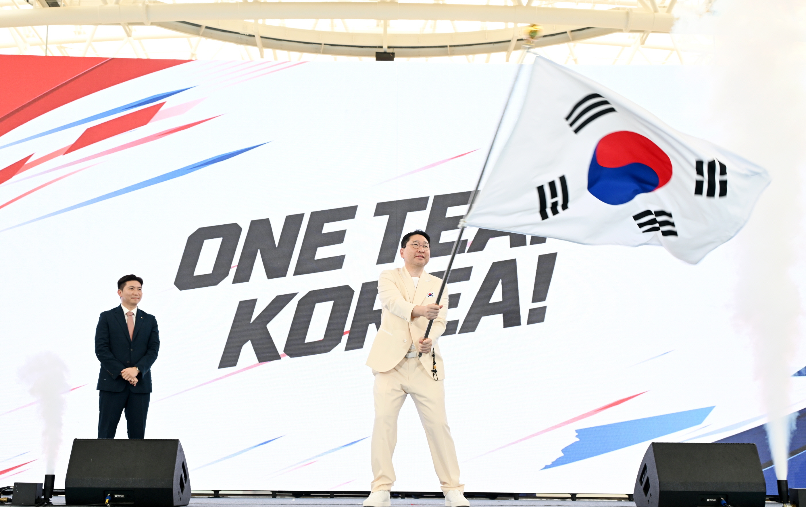 Lee Sang Hyun, head of the national delegation to the Aichi-Nagoya Asian Games in Japan, on Sept. 3 waves the national flag at the launching ceremony at Jincheon National Training Center in Jincheon-gun County, Chungcheongbuk-do Province. (Korean Sport and Olympic Committee)