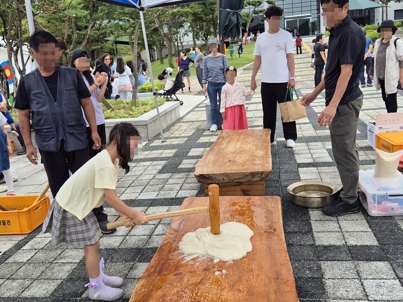 A girl pounds steamed rice for making tteok (rice cake) at a Chuseok cultural event from Oct. 3-7, 2025, at Jeonju National Museum in Jeonju, Jeollabuk-do Province. (Jeonju National Museum)