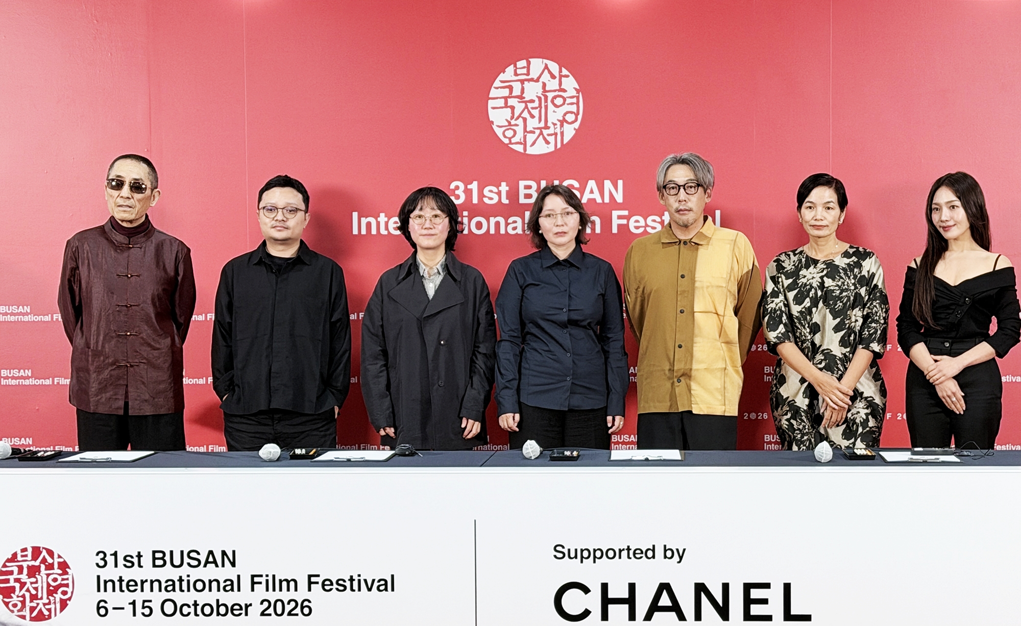 Attendees on Oct. 7, the second day of this year's Busan International Film Festival, pose for photos at a news conference for the Competition section at Busan Cinema Center in Busan's Haeundae-gu District. From left are jury president Zhang Yimou, directors Bi Gan and July Jung, actor Samal Yeslyamova, directors Kei Ishikawa and Tran Thi Bich Ngoc, and actor Choi Hee-seo. (Xu Aiying)