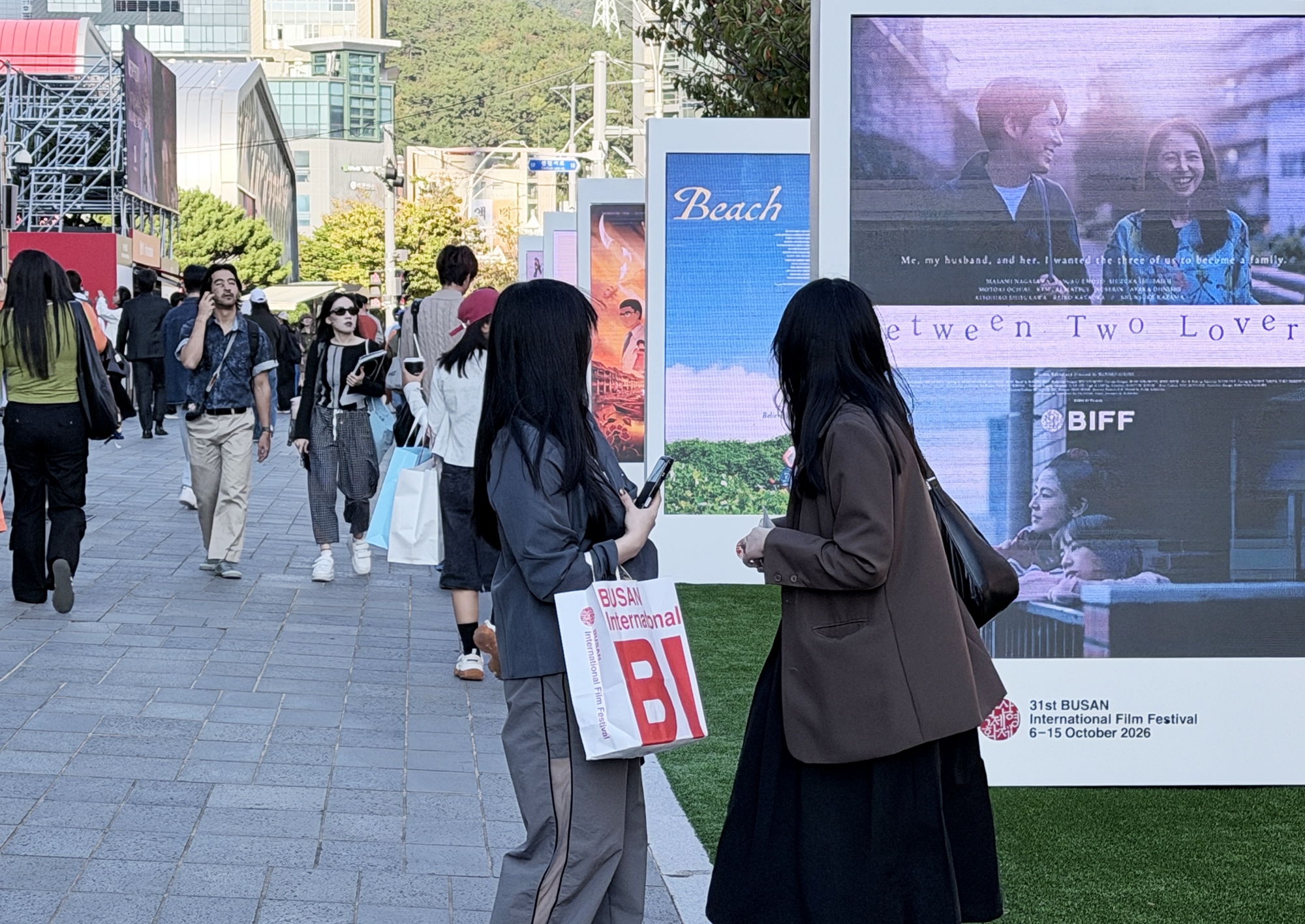 Visitors to the Busan International Film Festival on Oct. 7 walk past movie billboards around Busan Cinema Center in Busan's Haeundae-gu, Busan. (Xu Aiying)