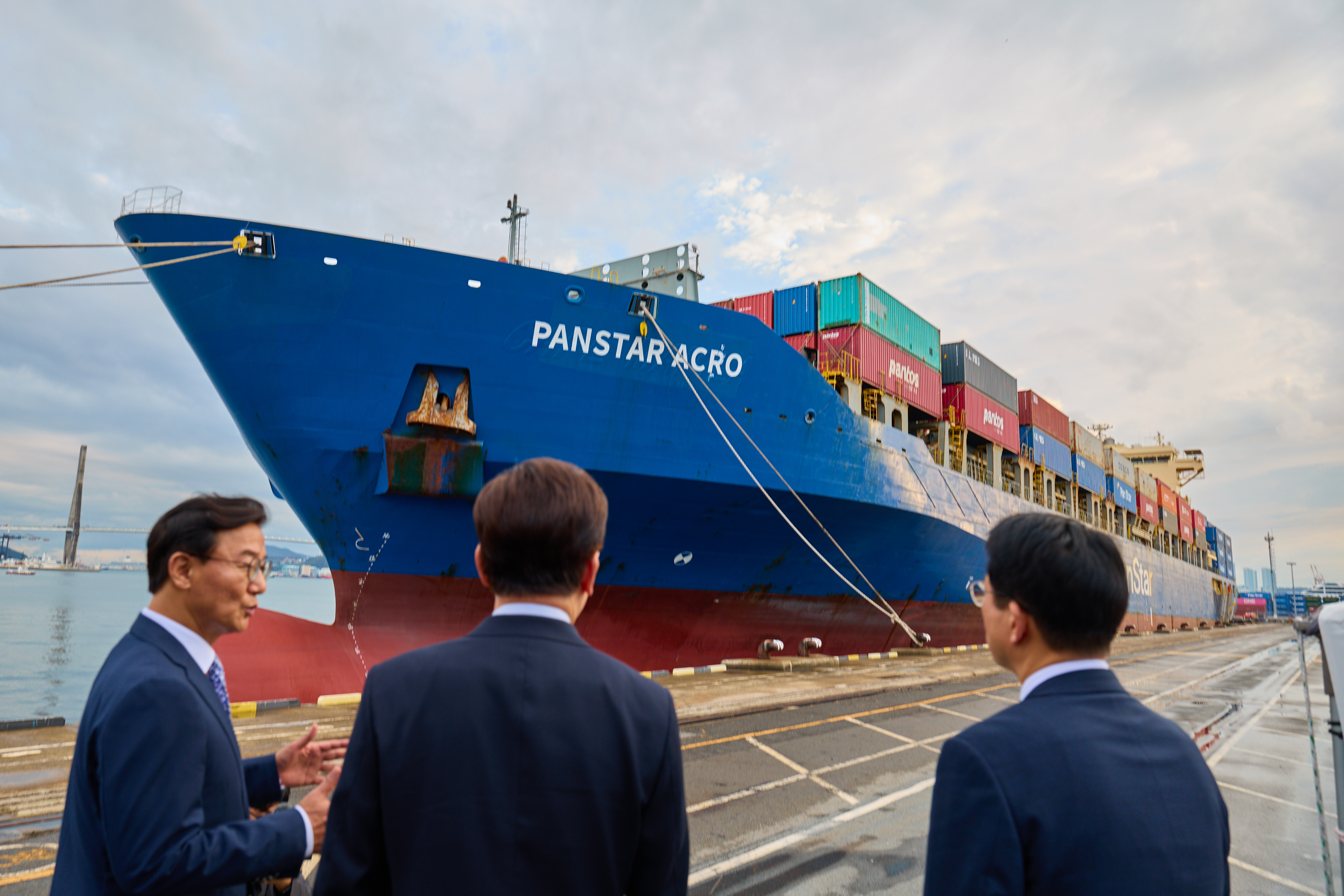 President Lee Jae Myung (center) on Oct. 13 is briefed on the Panstar Acro, a vessel that completed its pilot voyage on an Arctic shipping route two days earlier, at Pier 5 of Busan North Port in Busan's Dong-gu District.