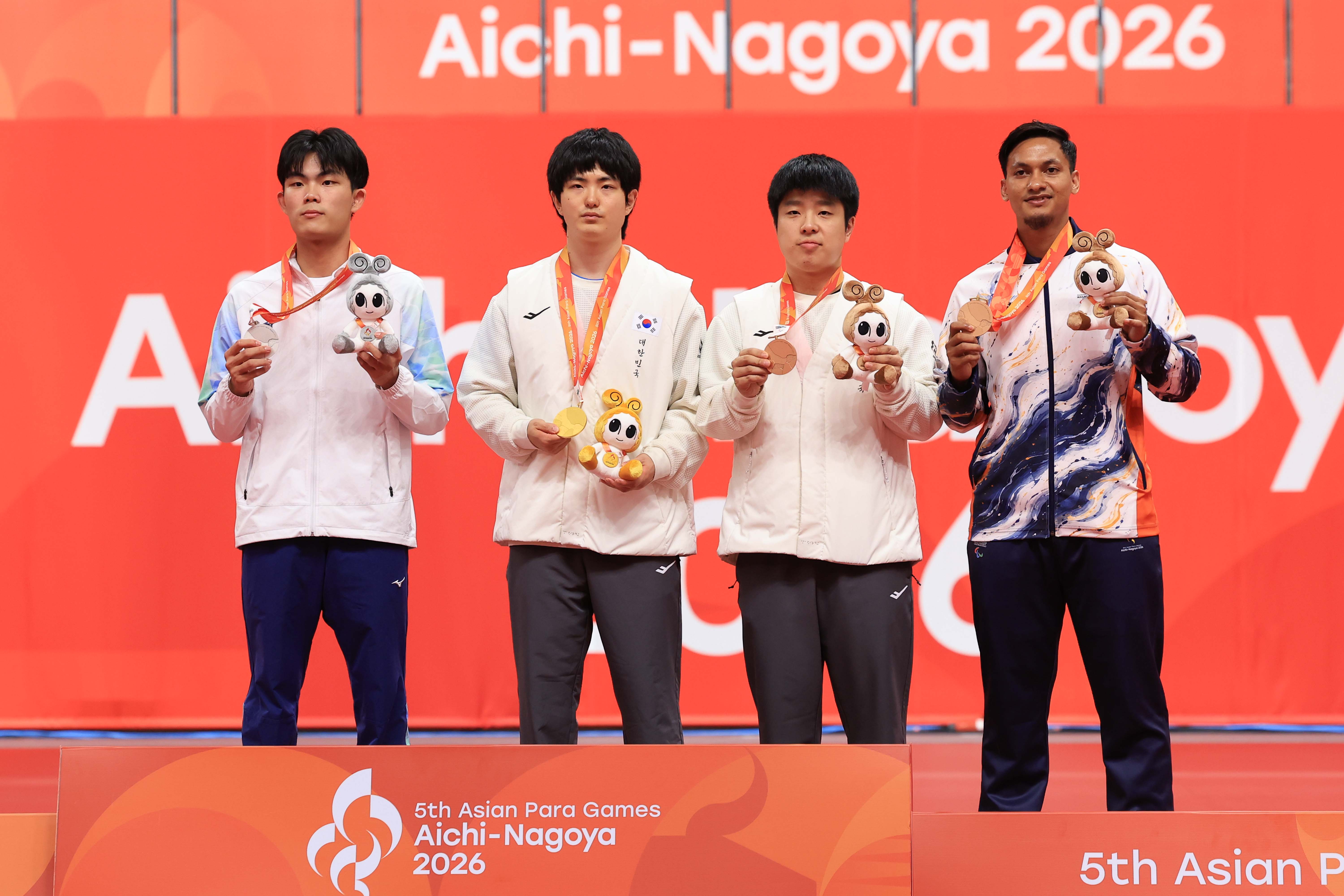 Gold medalist Kim Gitae (second from left) and bronze winner Kim Bogyeom (third from left) on Oct. 20 pose for a photo at the medal ceremony for men's singles Class 11 table tennis at the Aichi-Nagoya Asian Para Games in Japan at Sky Hall Toyota in Toyota, Aichi Prefecture.