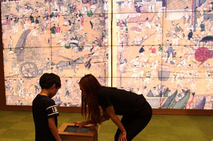 A young visitor to the Google Arts & Culture Pop-Up Lab at the National Museum of Korea on July 11 appreciates a gigapixel image of the <i>Taepyeongseongsido</i> (태평성시도, 太平城市圖), a famous Joseon-era painting.