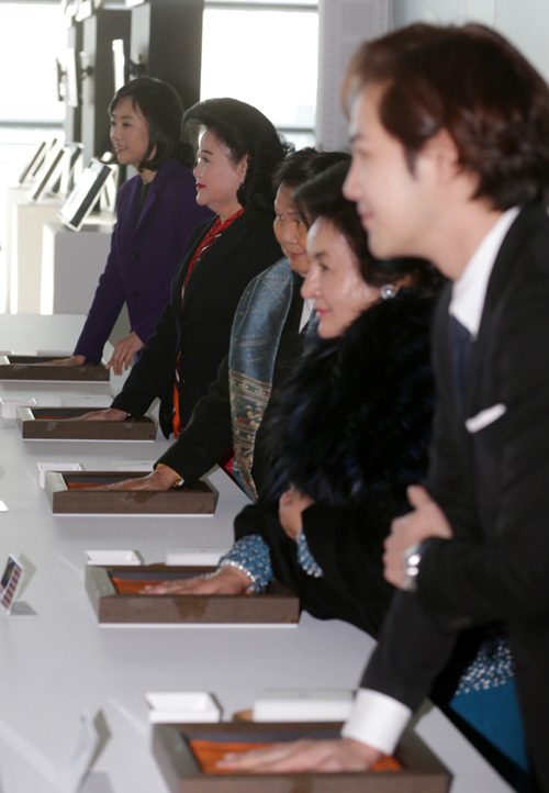 First ladies from Cambodia, Laos and Malaysia make a hand print together with actor Jang Keun-suk (right) at the Busan Cinema Center in Busan on December 12. 