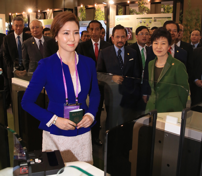 President Park Geun-hye (front, right) and leaders of the 10 ASEAN nations watch as a passport is issued with no paper work during their tour of an exhibition on innovation in public administration held at the BEXCO center in Busan on December 12. 