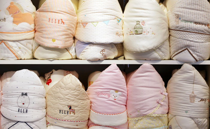 Newborn swaddling blankets are folded and on display at NEXTMOM. They are designed to cover and warm the newborn immediately upon birth.
