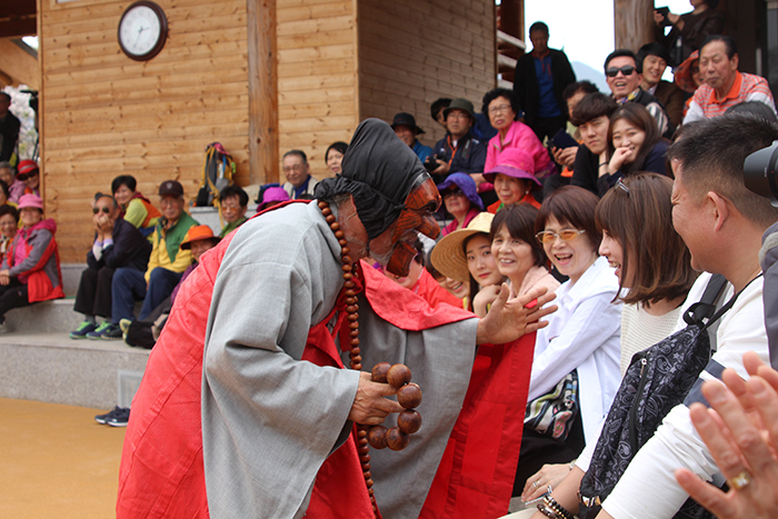 A performer in the <i>Hahoe-tal</i> mask play talks to the audience during a performance.