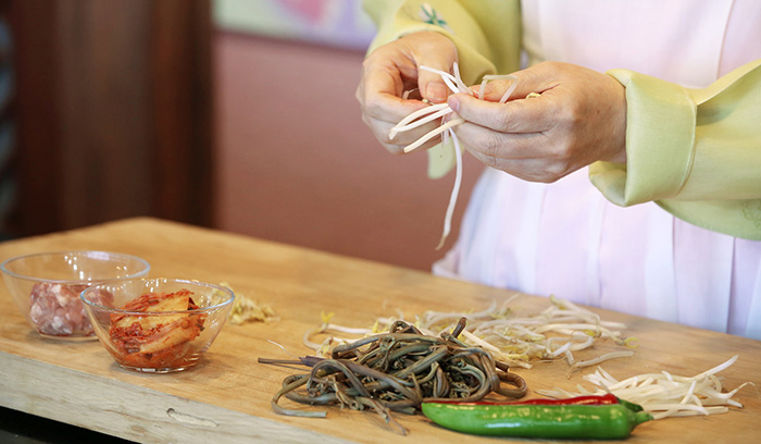 Remove the tough parts of the soaked bracken. Remove the tails of the bean sprouts and wash them in water. 