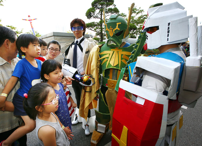 Young comic book fans gather with curiosity to inspect the actors wearing comic book hero costumes.