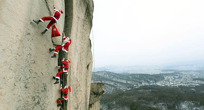 Dressed as Santa Claus, staff on the Bukhansan Mountain Rescue Police team climb the steep face of the mountain on December 21.