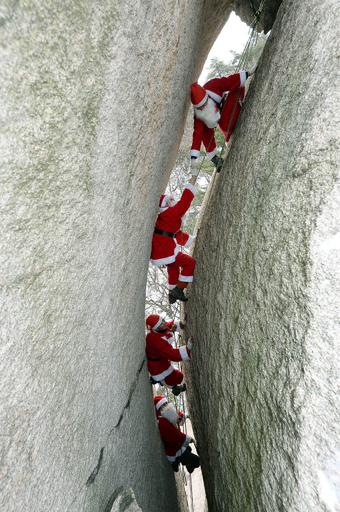 Kim Changgon (top), leader of the Bukhansan Mountain Rescue Police, helps his co-workers climb the Haegolbawi.