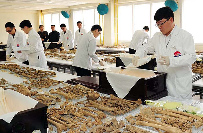 Korean medics place the remains of Chinese soldiers who were killed during the Korean War into coffins on March 17. (photo courtesy of Ministry of National Defense)