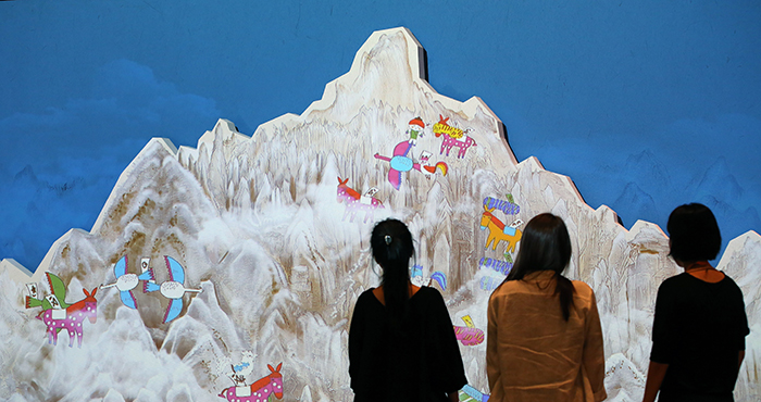 Staff at the Children’s Museum inspect the screen of the interactive video about traveling in ancient Korea.