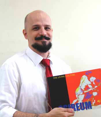 Professor Christopher Sparks poses for a photo, holding his recent English-language publication about <i>ssireum</i>, “SSIREUM- The Living Culture.” (photo: Sohn JiAe)