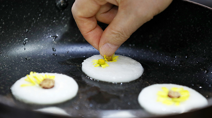 Place the chrysanthemum petals, pieces of jujube and other toppings on top to decorate the pancakes while cooking the second side in the pan. Make sure to cook them slowly over a very low heat.