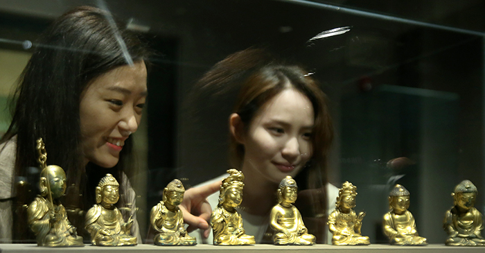 Visitors admire the miniature Buddha statues at the 'Devout Patrons of Buddhist Art' exhibit at the National Museum of Korea on May 22.