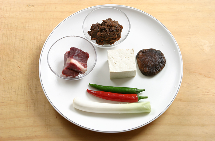The main ingredients of <i>doenjang jjigae</i> are soybean paste, beef, tofu, red and green peppers, and brown oak mushrooms.