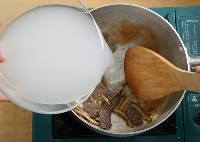 Add the beef and mushroom pieces to a preheated pot and stir fry them for 2 minutes over medium. Then add the rice-washed water.