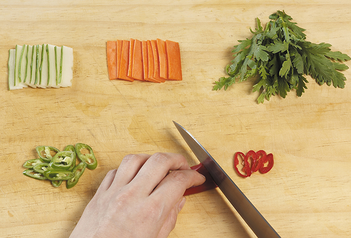 Wash and clean the cucumbers and carrots. Slice the cucumbers and carrots into rectangular, bite-sized pieces. Cut the green and red peppers into diagonal slices that are 2 cm long and 0.5 cm thick. Trim and wash the crown daisies and cut them into 5-cm lengths.