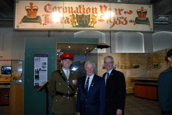 Banner artist Doug Leyland (center), a British Korean War veteran, poses under his painted banner which celebrates Queen Elizabeth II’s coronation in 1953, at the Royal Artillery Museum in Woolwich, London, on May 13.  